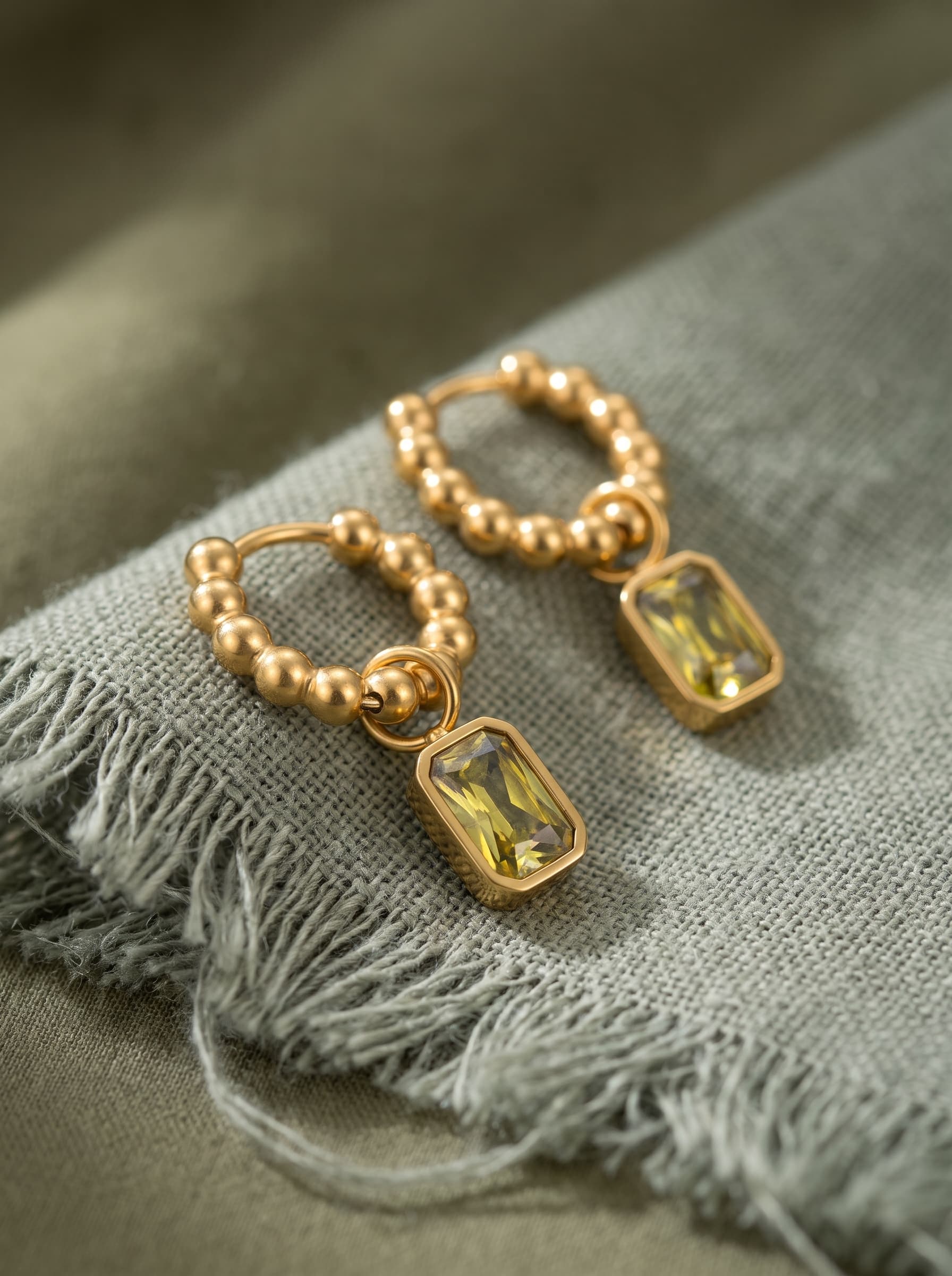 Olei Earrings on sage-green linen